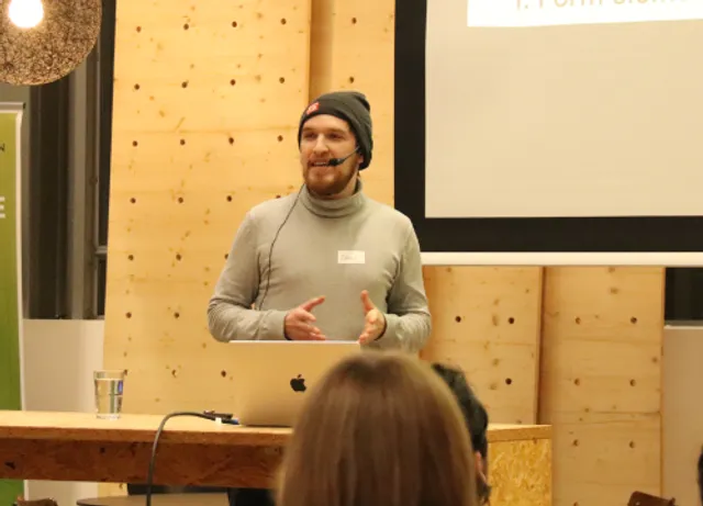 Denis Paris spricht auf der Bühne des OBI Tech Talks mit ansteck Mikrofon in Köln über Barrierefreie Webentwicklung